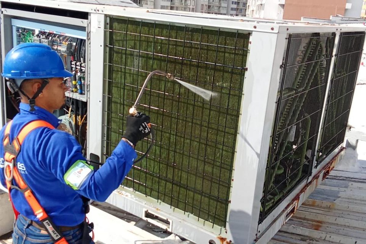 Técnico TecniAires limpiando condensador en techo de edificio en Barranquilla